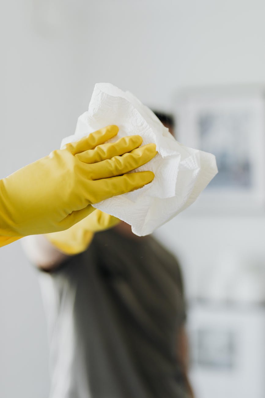 unrecognizable man cleaning mirror in bathroom